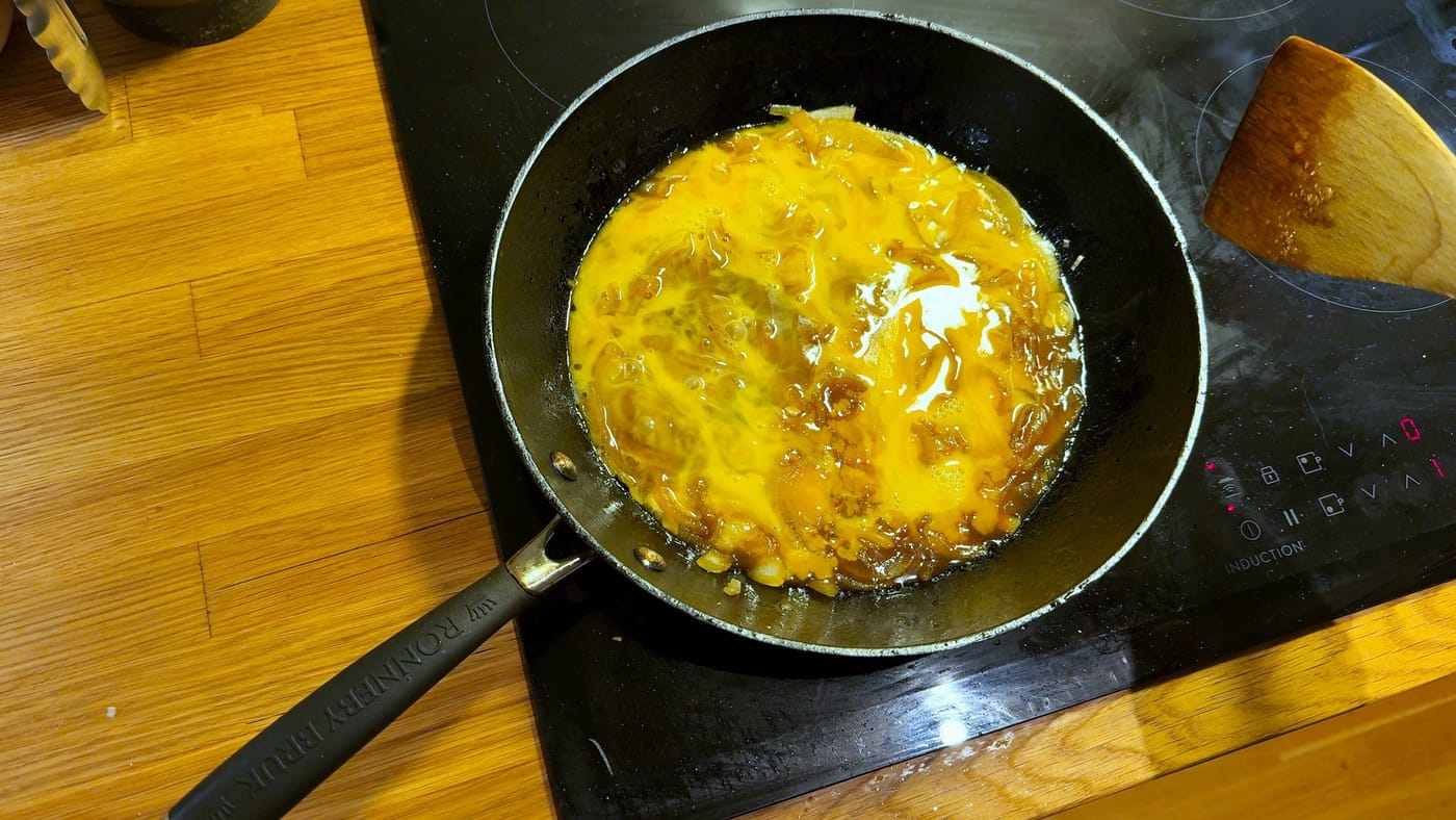 The egg setting over the onions in the pan